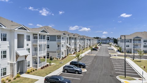 A row of houses with cars parked in front.
