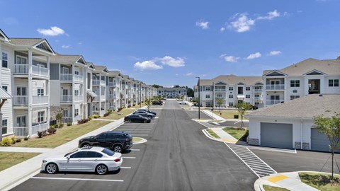 A row of white houses with cars parked in front.