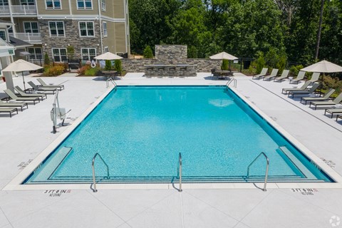 A large swimming pool surrounded by lounge chairs and umbrellas.