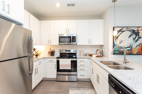 A modern kitchen with a stainless steel refrigerator and white cabinets.