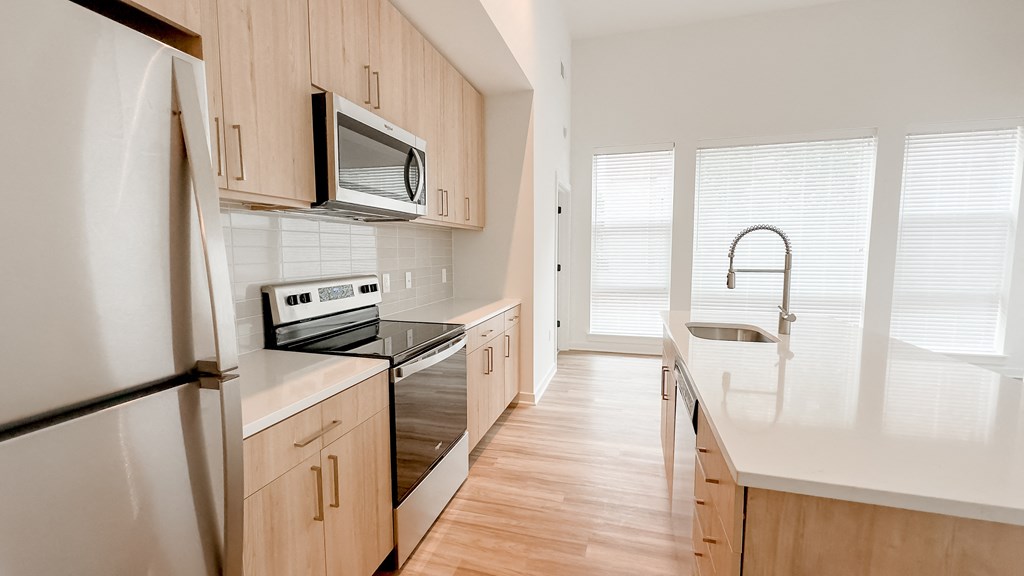 an empty kitchen with wooden cabinets and stainless steel appliances