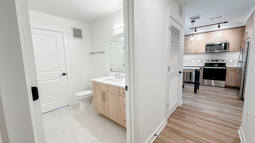 a renovated bathroom and kitchen with wood flooring and white walls