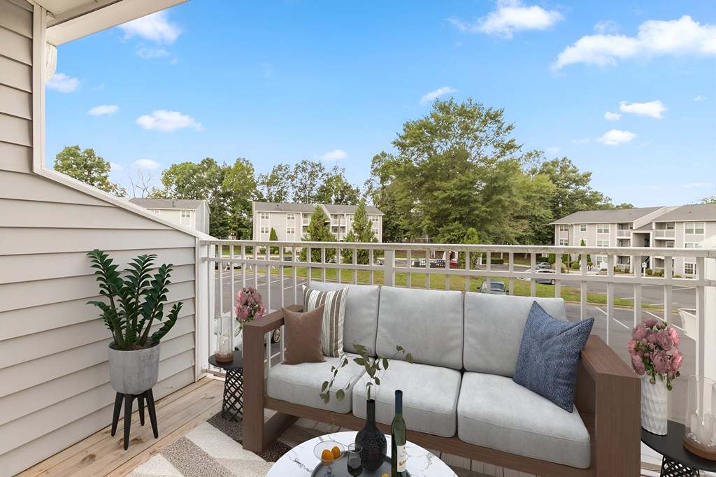 a patio with a couch and a table on a balcony at West Pointe Apartments in Burlington, NC