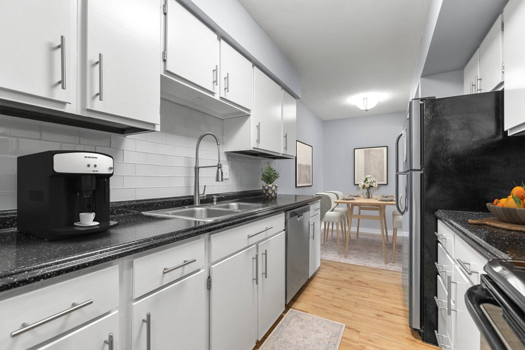 a kitchen with white cabinets and a sink and a refrigerator at West Pointe Apartments in Burlington, NC