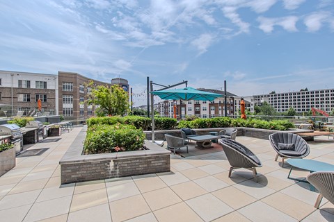A patio with chairs and tables is surrounded by buildings.