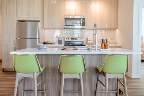 a kitchen with green stools in front of a counter top