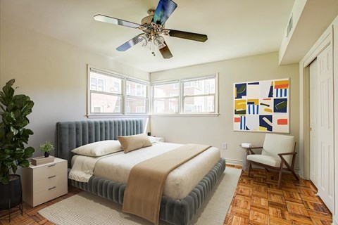 A bedroom with a bed, a ceiling fan, and a painting on the wall.