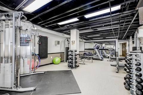 A gym with a variety of equipment including weights and a bench. at Park Georgetown Apartments, Arlington, Virginia