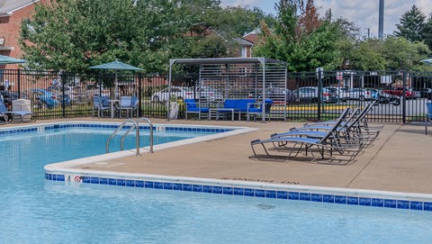 A swimming pool with a blue tiled edge and a metal fence around it.