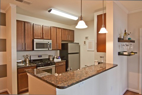 A kitchen with a granite counter top and wooden cabinets.