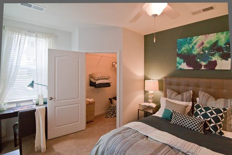 A bedroom with a large bed and a painting on the wall.