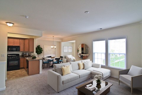 A well-lit, spacious living room with a kitchen area in the background.