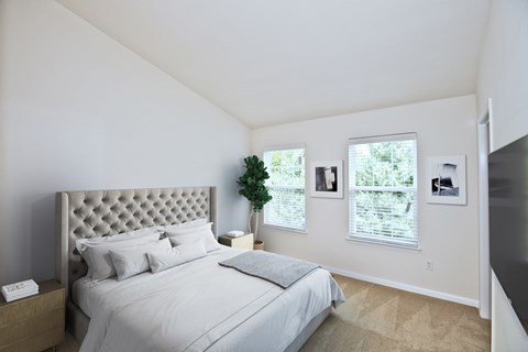 A bedroom with a large bed and a potted plant on the nightstand.
