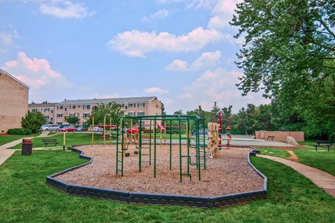 A playground with a red swing set and a green slide.