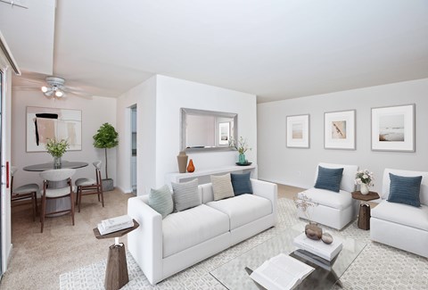 A living room with white furniture and a glass coffee table.