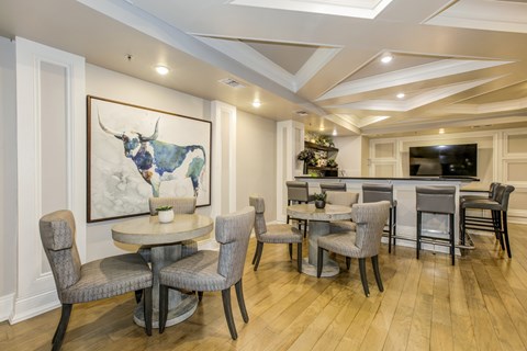 A dining room with a table and chairs and a painting of a bull on the wall.