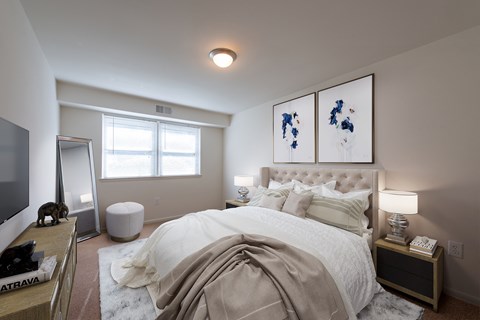 A bedroom with a large bed and two framed pictures on the wall.