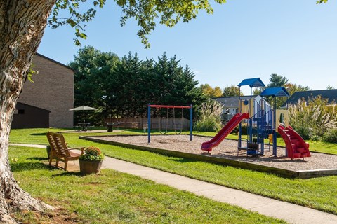 A playground with a red slide and a blue canopy.