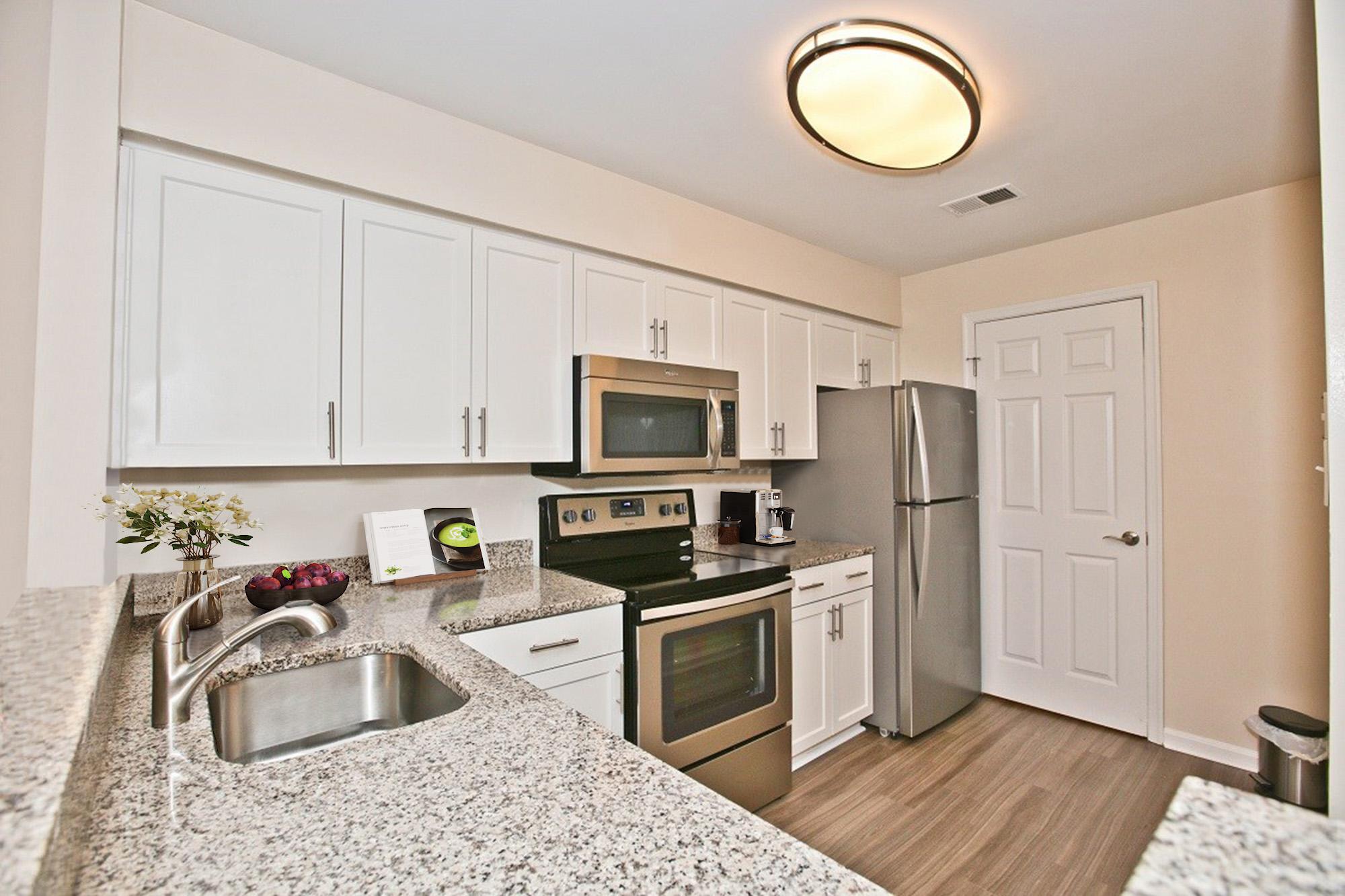 A kitchen with white cabinets and a granite countertop.