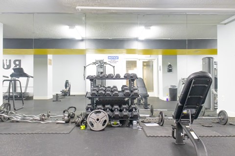 A gym with a variety of equipment including weights and a leg press machine.