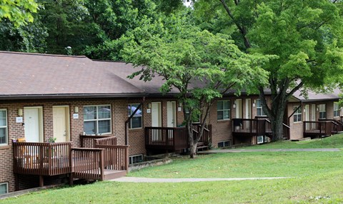 an exterior view of a brick building with a porch and trees