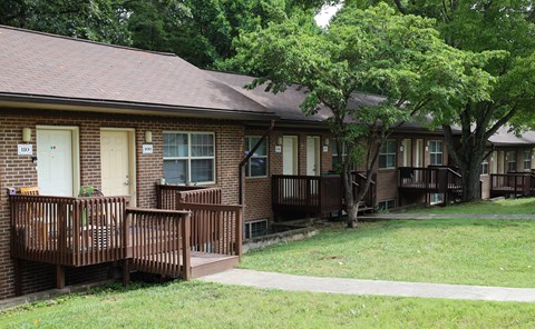 an exterior view of a brick house with a porch and a tree