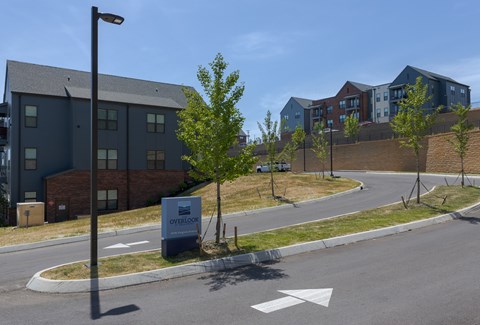 A street view of a residential area with apartment buildings and a sign that reads "Overlook".