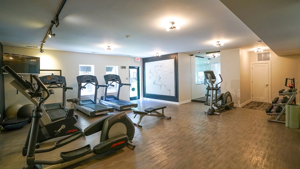 a gym with treadmills and other exercise equipment on a wood floor