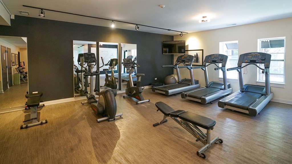 a gym with cardio equipment and weights on a wood floor