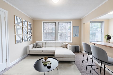 A living room with a white couch, a coffee table, and a window with blinds.