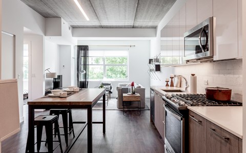 A modern kitchen with a wooden table and stools.