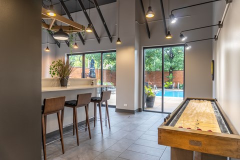 A room with a pool table and bar stools.