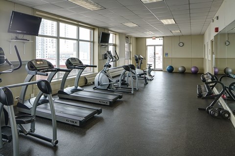 A gym with treadmills, elliptical machines, and exercise balls.