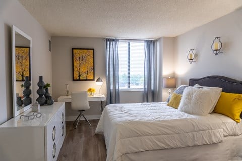 A bedroom with a large bed and a desk with a chair.