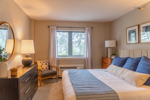 A bedroom with a large bed and a window with curtains.