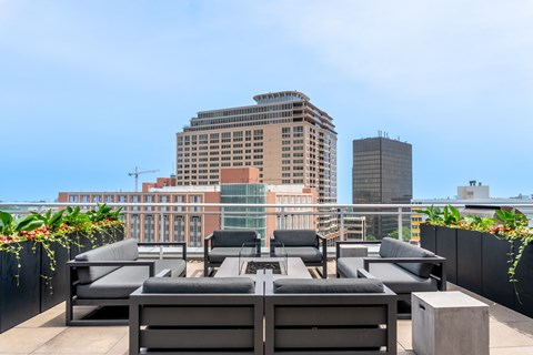 A rooftop patio with black furniture and plants.
