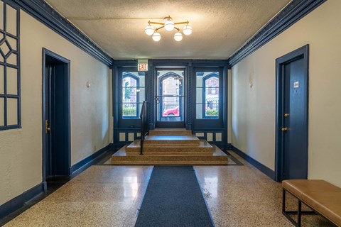 A hallway with a bench, a door, and a window.