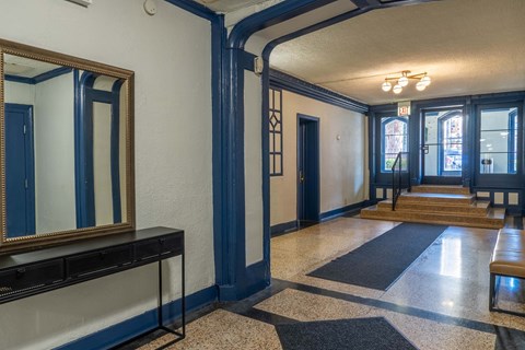 A hallway with a mirror on the left and a bench on the right.
