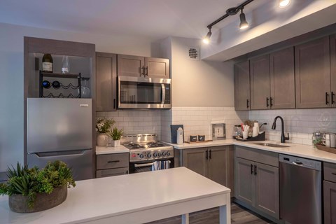 A modern kitchen with a white countertop and stainless steel appliances.