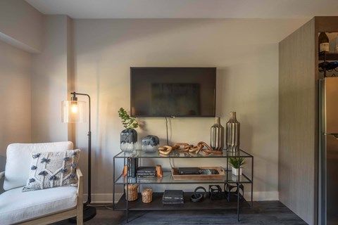 A living room with a white chair and a glass display table.