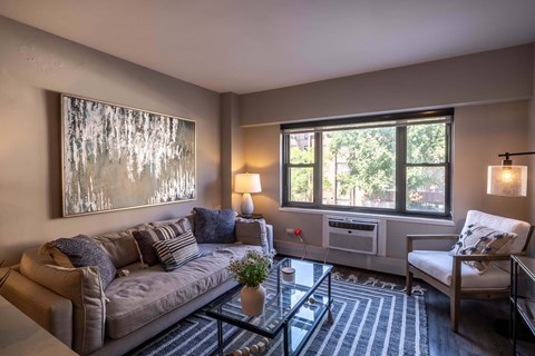 A living room with a grey couch, a coffee table, and a painting on the wall.