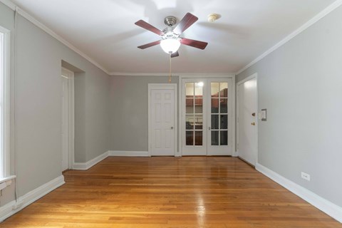 A room with a ceiling fan and wooden floors.