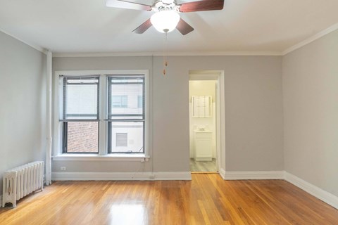 A room with a ceiling fan and a window with blinds.