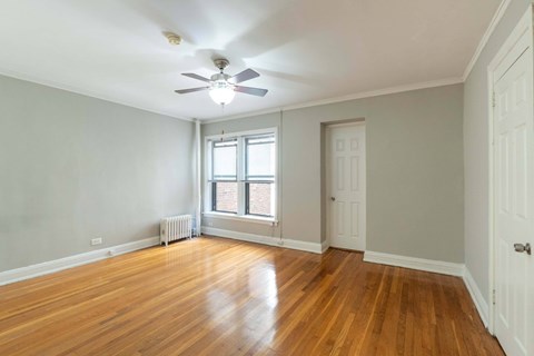 A room with a ceiling fan and wooden floors.