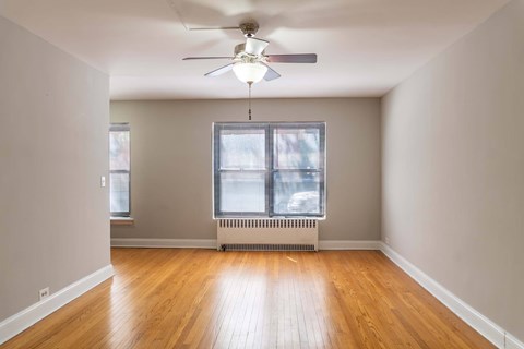 A room with a ceiling fan and a window with blinds.