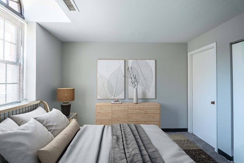A bedroom with a bed, nightstand, lamp, and two paintings on the wall.