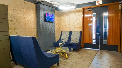 A room with blue chairs and a TV on the wall.