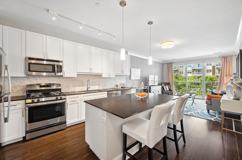 A modern kitchen with white cabinets and a black island.
