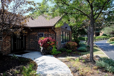 A house with a brick exterior and a tree with red leaves in front.