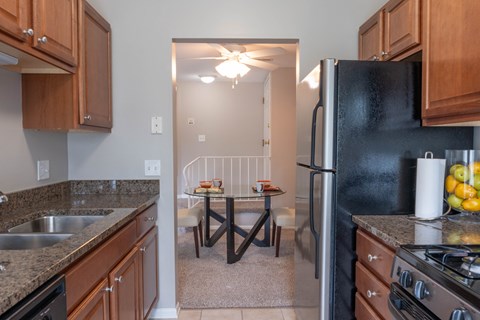A kitchen with a black refrigerator and a table with chairs in the background.